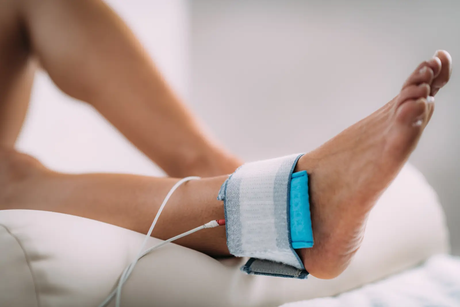 A cuff and sensor fitted around a patient's ankle during a vascular blood-flow test.