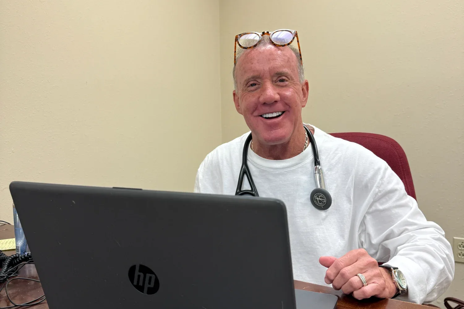 Dr. Jeffrey Tauth smiling at his desk, wearing a stethoscope